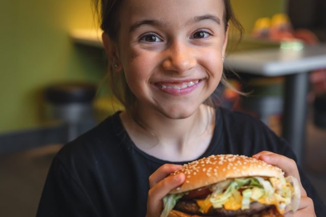 a-little-girl-eats-an-appetizing-burger-close-up-2023-11-27-05-35-52-utc